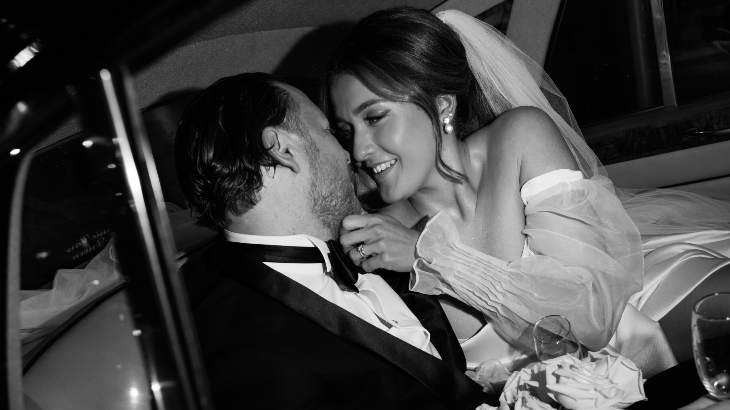 Happy couple sharing a kiss in a car, beautifully captured by Art of Grace Photography, showcasing their romantic wedding moment with expert photography that highlights timeless elegance and love.